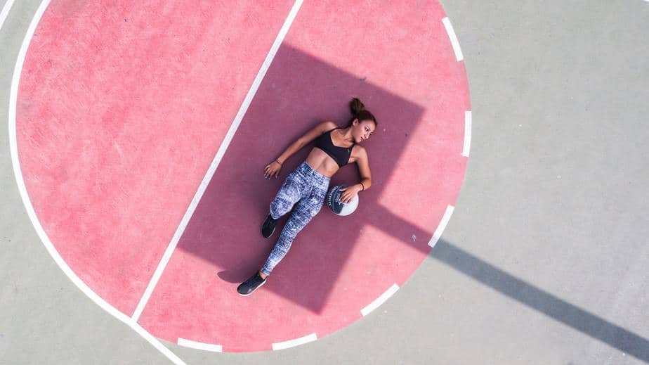 young-woman-lying-on-pink-court-with-ball